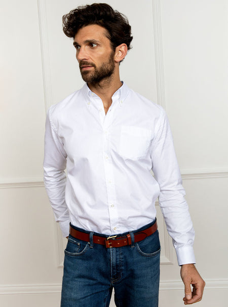 Man wearing white long sleeved shirt with button down collar and the inside collar and cuffs trimmed with sky blue. Made with 100% cotton in Thomas Mason fabric.